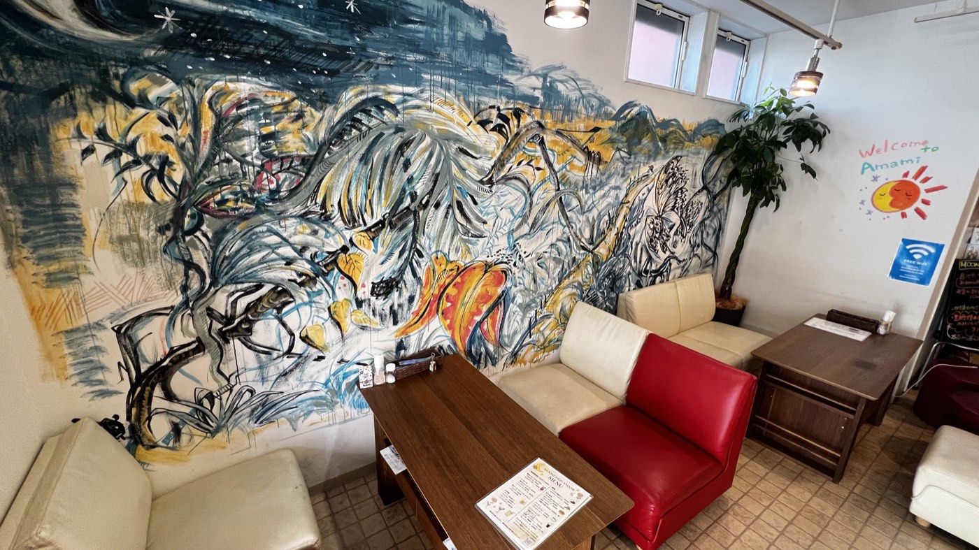 壁一面に描かれた奄美の自然の壁画と、ソファ席