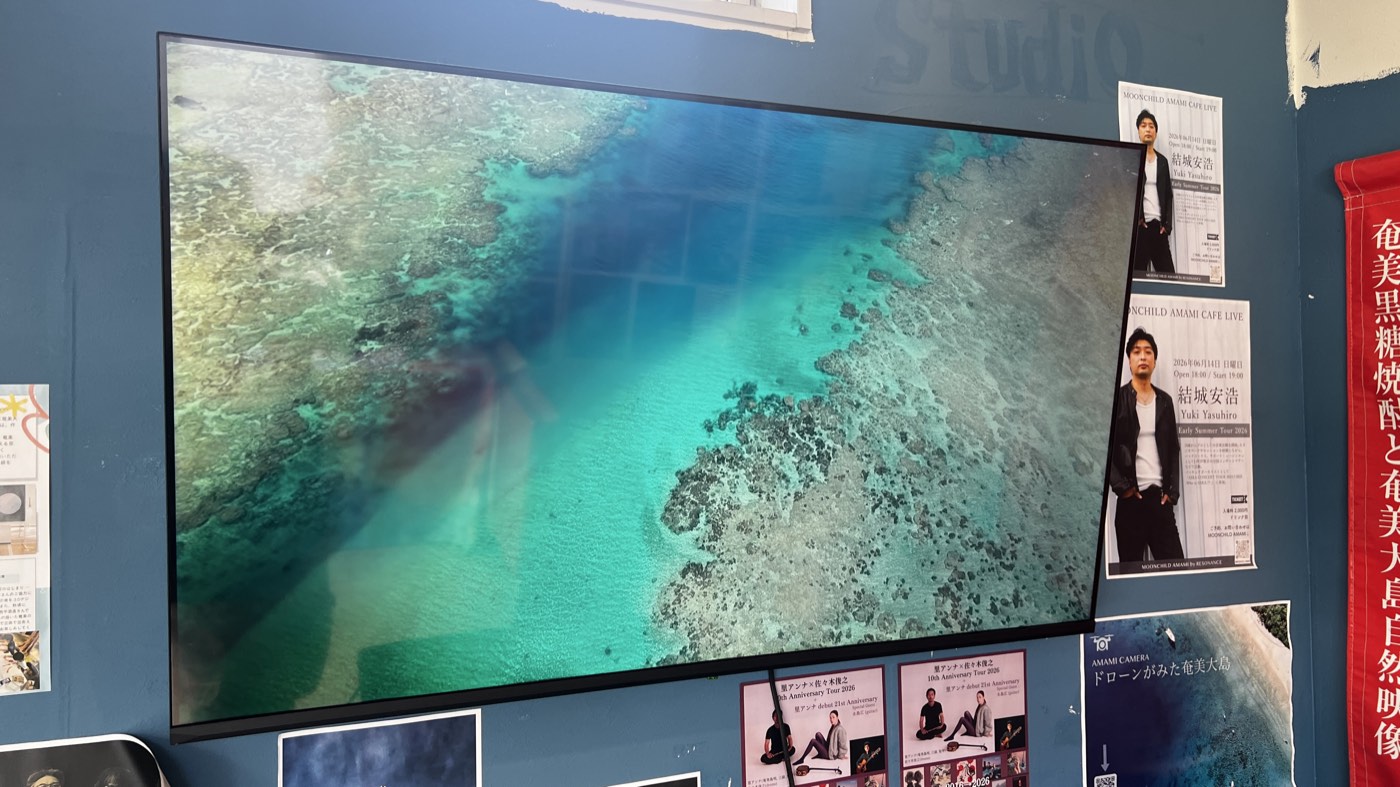 店内の大画面に映る、ドローンで撮影した奄美大島のサンゴ礁